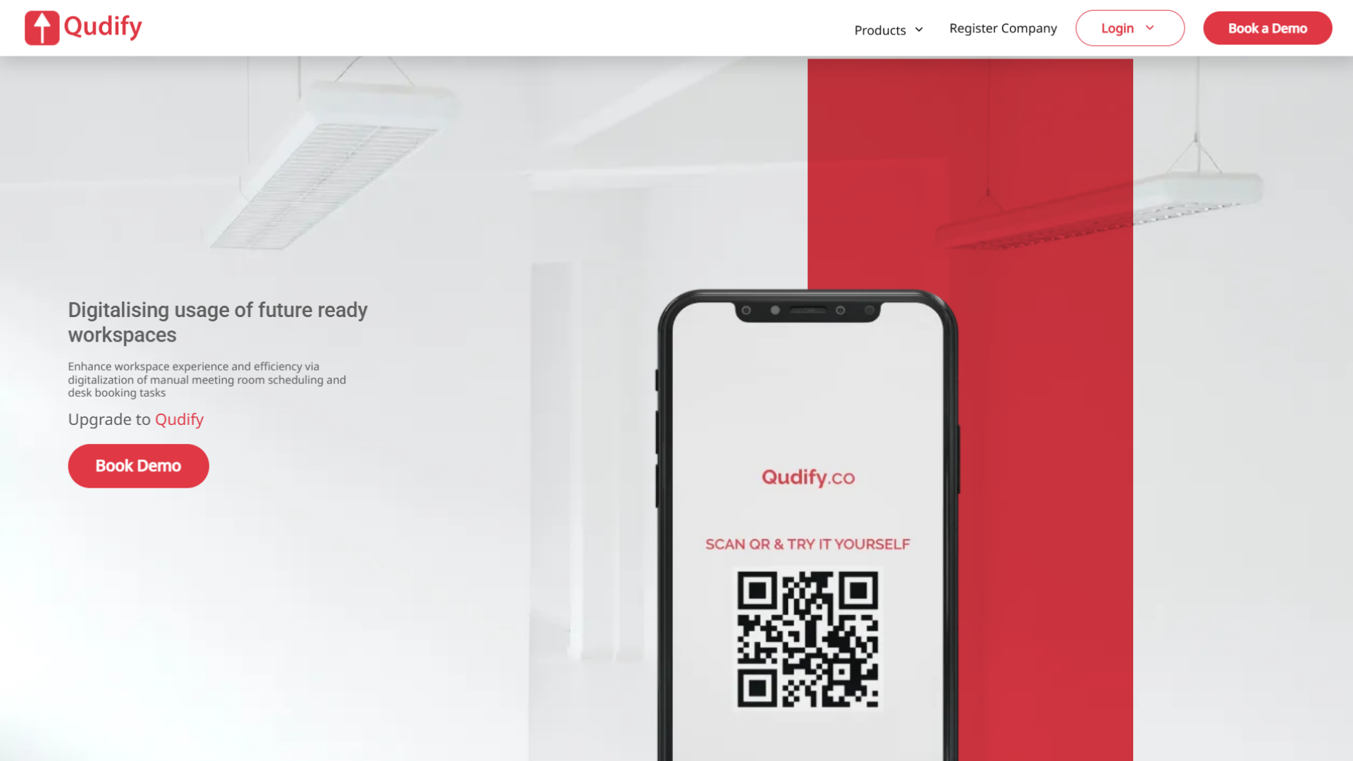 Qudify website homepage featuring the Qudify logo, top navigation menu with products, register company, login, and Book a Demo buttons, headline Digitalising usage of future ready workspaces, subtext about enhancing workspace experience and efficiency via digitalization of manual meeting room scheduling and desk booking tasks, an upgrade call to action with a Book Demo button, and a central smartphone mockup displaying a QR code and the text Qudify.co and SCAN QR & TRY IT YOURSELF.